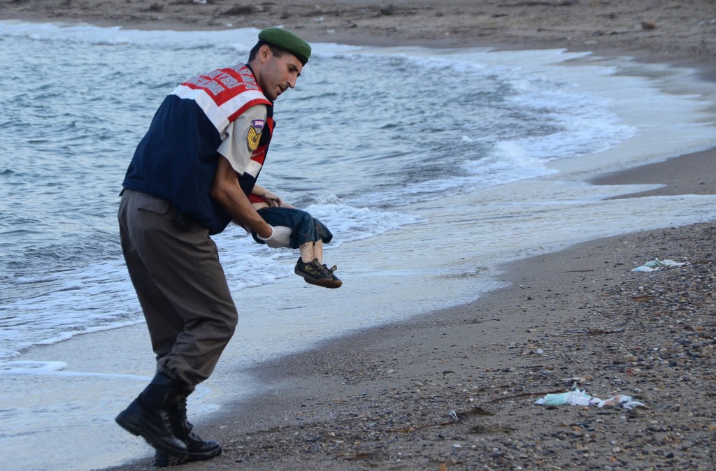 GRAPHIC CONTENT A Turkish police officer carries a migrant child's dead body off the shores in Bodrum, southern Turkey, on September 2, 2015 after a boat carrying refugees sank while reaching the Greek island of Kos. Thousands of refugees and migrants arrived in Athens on September 2, as Greek ministers held talks on the crisis, with Europe struggling to cope with the huge influx fleeing war and repression in the Middle East and Africa. AFP PHOTO / DOGAN NEWS AGENCY = TURKEY OUT =
